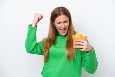 Foto de Young caucasian woman holding fried chips isolated on white background celebrating a victory - Imagen libre de derechos