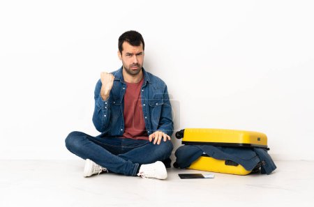 Téléchargez les photos : Blanc bel homme avec une valise pleine de vêtements assis sur le sol à l'intérieur avec une expression malheureuse - en image libre de droit
