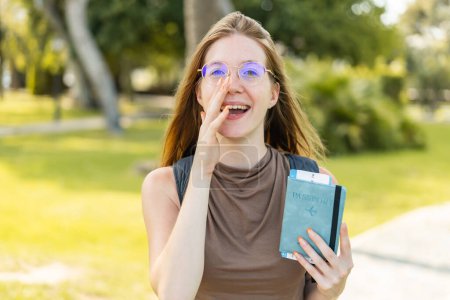 Téléchargez les photos : Française avec des lunettes tenant un passeport à l'extérieur criant avec la bouche grande ouverte - en image libre de droit