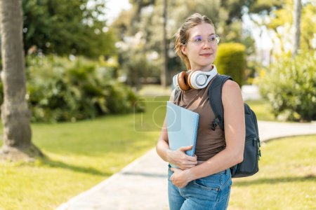 Photo for Young French girl with glasses at outdoors holding a notebook with happy expression - Royalty Free Image