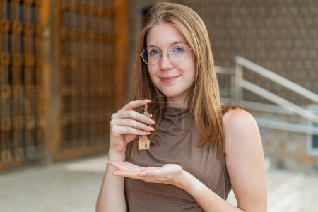 Téléchargez les photos : Jeune fille française avec des lunettes à l'extérieur tenant les clés de la maison avec expression heureuse - en image libre de droit