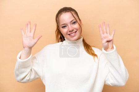 Téléchargez les photos : Jeune femme caucasienne isolée sur fond beige comptant neuf avec les doigts - en image libre de droit