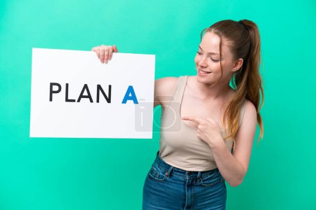 Young caucasian woman isolated on green background holding a placard with the message PLAN A and  pointing it