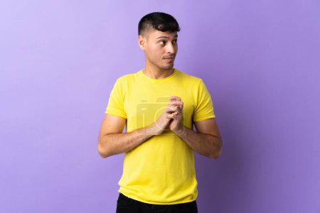 Photo for Young Colombian man isolated on purple background scheming something - Royalty Free Image