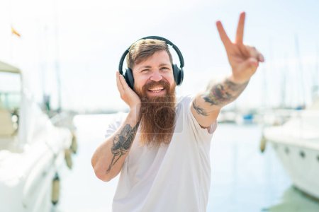 Foto de Pelirrojo con barba escuchando música y cantando - Imagen libre de derechos