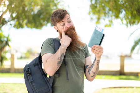 Téléchargez les photos : Rousse homme avec barbe tenant un passeport à l'extérieur - en image libre de droit