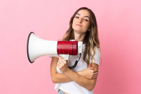 Photo for Young Romanian woman isolated on pink background holding a megaphone and smiling - Royalty Free Image