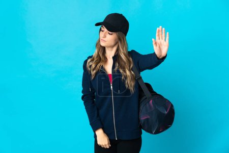 Photo for Young Romanian sport woman with sport bag isolated on blue background making stop gesture and disappointed - Royalty Free Image