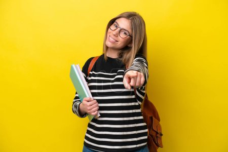 Téléchargez les photos : Jeune étudiante femme isolée sur fond jaune pointant devant avec une expression heureuse - en image libre de droit