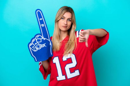 Uruguayan sports fan woman isolated on blue background showing thumb down with negative expression