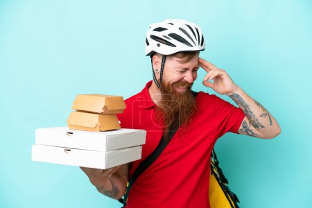 Téléchargez les photos : Livreur tenant pizzas et hamburgers isolés sur fond bleu riant - en image libre de droit