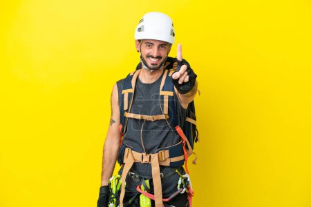 Photo for Young caucasian rock climber man isolated on yellow background showing and lifting a finger - Royalty Free Image