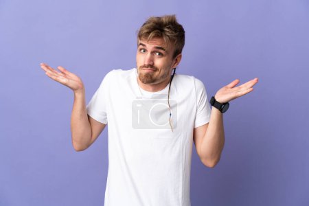 Photo for Young handsome blonde man isolated on purple background having doubts while raising hands - Royalty Free Image