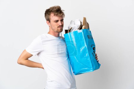 Photo for Young blonde man holding a recycling bag full of paper to recycle isolated on white background suffering from backache for having made an effort - Royalty Free Image