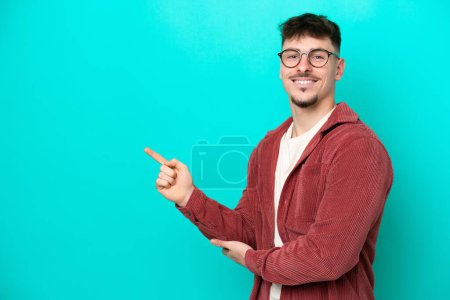 Photo for Young caucasian handsome man isolated on blue background pointing finger to the side - Royalty Free Image