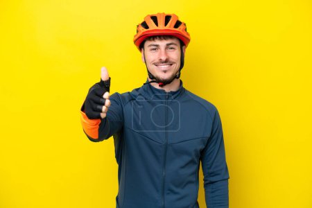 Photo for Young cyclist caucasian man isolated on yellow background with thumbs up because something good has happened - Royalty Free Image