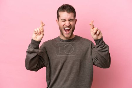 Photo for Young caucasian man isolated on pink background with fingers crossing - Royalty Free Image