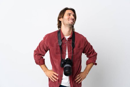 Téléchargez les photos : Jeune photographe homme isolé sur fond blanc posant les bras à la hanche et souriant - en image libre de droit