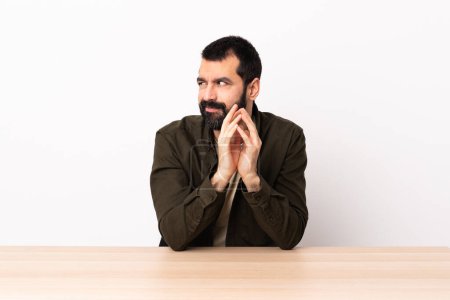 Téléchargez les photos : Homme caucasien avec barbe dans une table comploter quelque chose
. - en image libre de droit