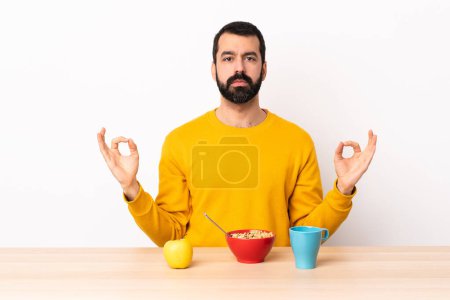 Téléchargez les photos : Homme caucasien prendre le petit déjeuner dans une table dans zen pose
. - en image libre de droit