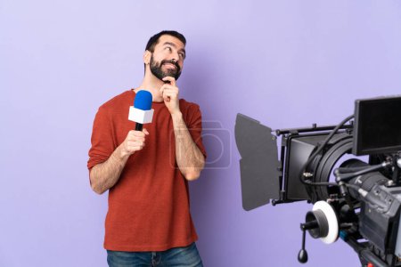 Téléchargez les photos : Reporter homme tenant un microphone et rapportant des nouvelles sur fond violet isolé penser une idée tout en levant les yeux - en image libre de droit