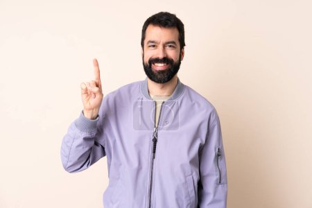 Téléchargez les photos : Homme caucasien avec barbe portant une veste sur fond isolé montrant et levant un doigt en signe du meilleur - en image libre de droit