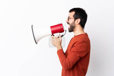 Photo for Caucasian handsome man with beard over isolated white background shouting through a megaphone - Royalty Free Image