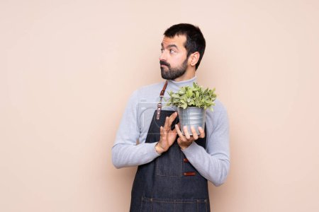 Téléchargez les photos : Un homme tenant une plante sur un fond isolé complotant quelque chose - en image libre de droit