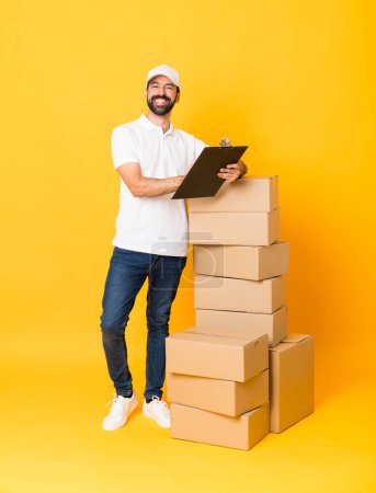 Photo for Full-length shot of delivery man among boxes over isolated yellow background - Royalty Free Image