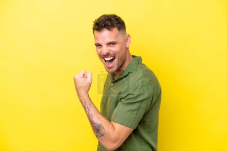Photo for Young caucasian handsome man isolated on yellow background celebrating a victory - Royalty Free Image