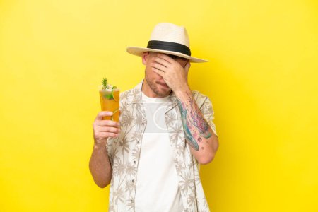 Photo for Young caucasian man holding a cocktail isolated on yellow background with tired and sick expression - Royalty Free Image