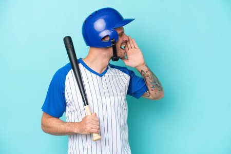 Photo for Baseball player with helmet and bat isolated on blue background shouting with mouth wide open to the side - Royalty Free Image