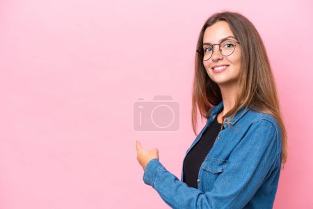 Photo for Young caucasian woman isolated on pink background pointing back - Royalty Free Image