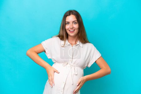 Photo for Young caucasian woman isolated on blue background pregnant and doing surprise gesture - Royalty Free Image