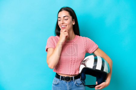 Photo for Young caucasian woman with a motorcycle helmet isolated on blue background looking to the side and smiling - Royalty Free Image