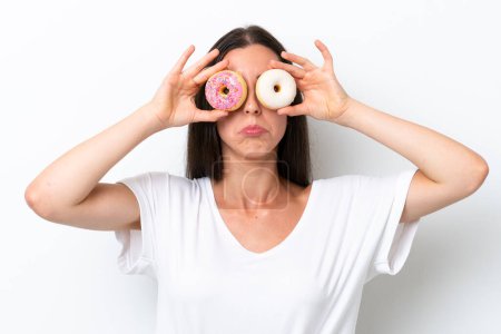 Photo for Young caucasian woman isolated on white background holding donuts in eyes with sad expression - Royalty Free Image