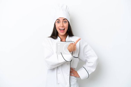 Photo for Young chef woman over white background surprised and pointing side - Royalty Free Image