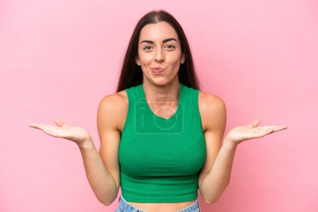 Photo for Young caucasian woman isolated on pink background having doubts while raising hands - Royalty Free Image