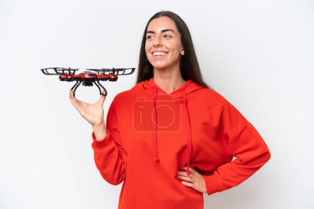 Photo for Young caucasian woman holding a drone isolated on white background posing with arms at hip and smiling - Royalty Free Image
