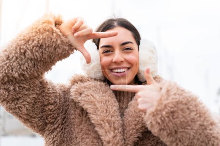 Téléchargez les photos : Jeune femme portant des manchons d'hiver à l'extérieur en se concentrant visage. Symbole d'encadrement - en image libre de droit