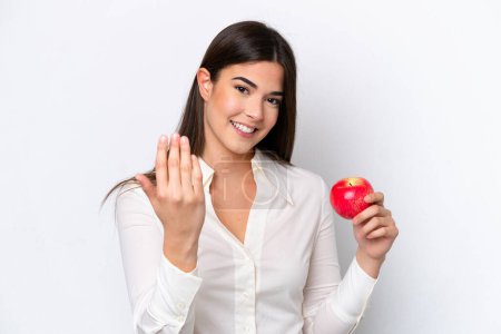 Téléchargez les photos : Jeune femme brésilienne avec une pomme isolée sur fond blanc invitant à venir avec la main. Heureux que tu sois venu - en image libre de droit