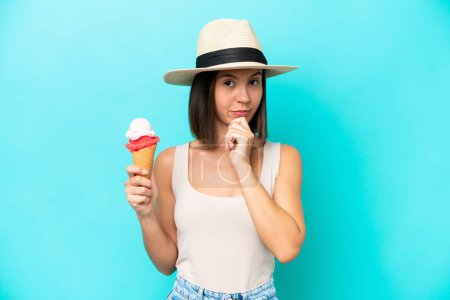 Téléchargez les photos : Jeune femme caucasienne tenant une crème glacée isolée sur fond bleu pensée - en image libre de droit