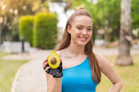 Photo for Young pretty sport girl holding an avocado at outdoors smiling a lot - Royalty Free Image