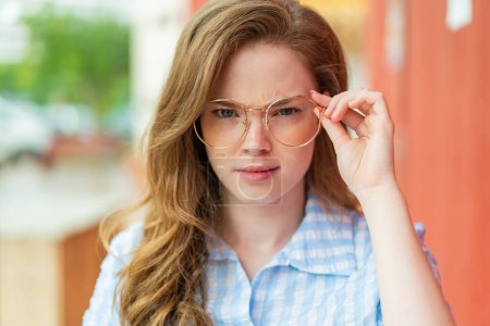 Photo for Young redhead woman at outdoors With glasses and frustrated expression - Royalty Free Image