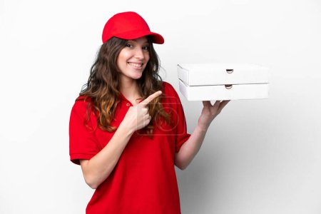 Téléchargez les photos : Pizza delivery woman with work uniform picking up pizza boxes isolated on white background pointing to the side to present a product - en image libre de droit