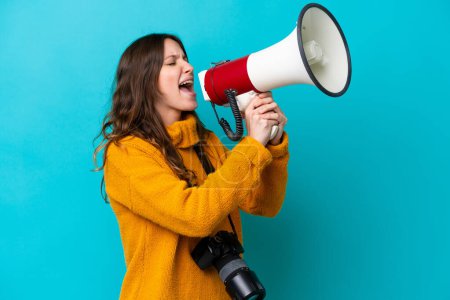 Photo for Young photographer woman isolated on blue background shouting through a megaphone - Royalty Free Image