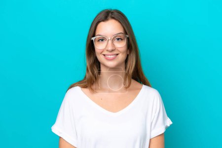 Téléchargez les photos : Jeune femme caucasienne isolée sur fond bleu Avec des lunettes avec une expression heureuse - en image libre de droit