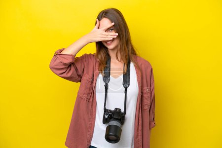 Photo for Young photographer caucasian woman isolated on yellow background covering eyes by hands and smiling - Royalty Free Image