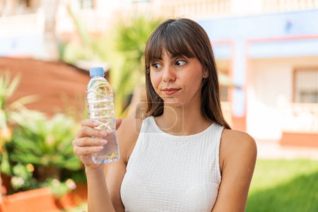 Photo for Young woman with a bottle of water at outdoors with sad expression - Royalty Free Image