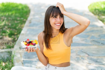 Téléchargez les photos : Jeune femme tenant un bol de fruits à l'extérieur a réalisé quelque chose et l'intention de la solution - en image libre de droit